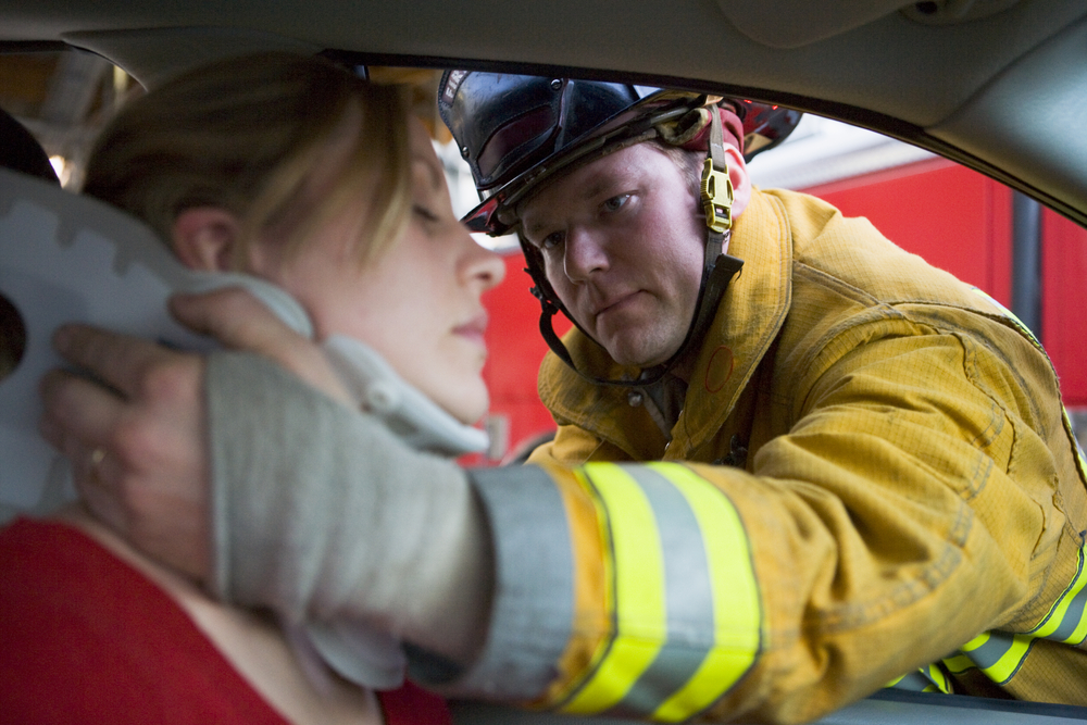 What happens if my spouse is at fault for an accident and I suffer injuries? - Firefighters helping an injured woman in a car